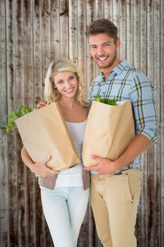 Attractive couple holding their grocery bags against wooden planks