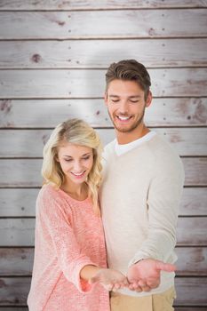 Attractive couple holding their hands out against wooden planks