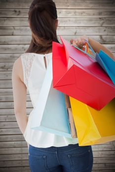Rear view of brown hair holding shopping bags against wooden planks background