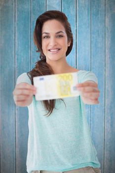 Pretty brunette showing a bill against wooden planks