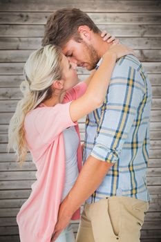 Attractive young couple about to kiss against wooden planks background