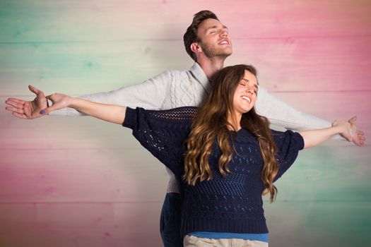 Romantic young couple with arms out against pink and green planks