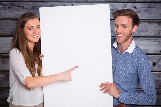 Happy young couple with blank board against grey wooden planks