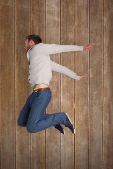 Full length of cheerful young man jumping against wooden planks background