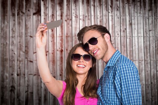 Couple taking selfie with smart phone against wooden planks