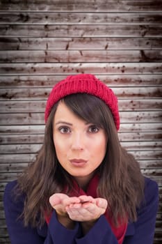 Festive brunette blowing over hands against wooden planks