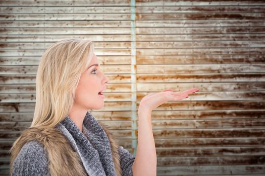 Blonde in winter clothes with hand out against wooden planks