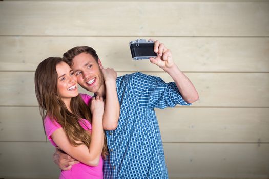 Couple taking selfie with digital camera against bleached wooden planks background