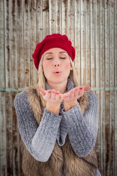 Blonde in winter clothes with hands out against wooden planks