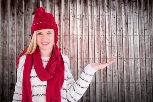 Festive blonde presenting with hand against wooden planks
