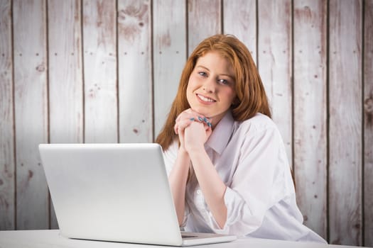 Pretty redhead working on laptop against wooden planks