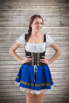 Pretty oktoberfest girl with hands on hips against wooden planks background