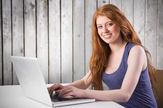 Pretty redhead working on laptop against wooden planks