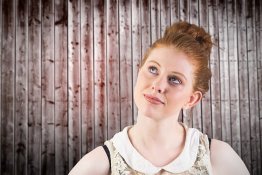 Hipster redhead looking up thinking against wooden planks