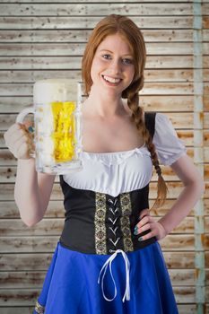 Oktoberfest girl smiling at camera holding beer against faded pine wooden planks