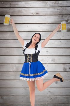 Pretty oktoberfest girl holding beer tankards against wooden planks