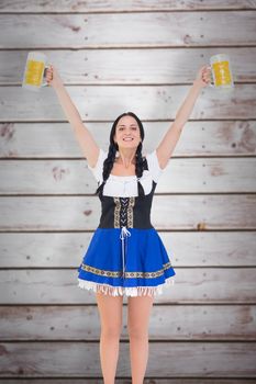 Pretty oktoberfest girl holding beer tankards against wooden planks