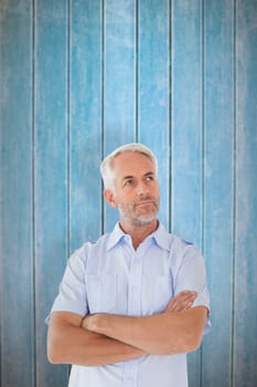 Thinking man posing with arms crossed against wooden planks