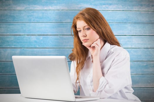 Pretty redhead working on laptop against wooden planks