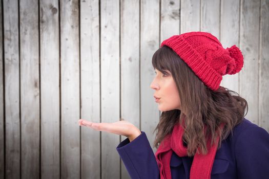 Festive brunette blowing a kiss against wooden planks