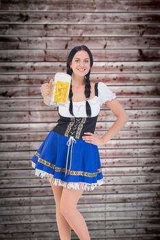 Pretty oktoberfest girl holding beer tankard against wooden planks