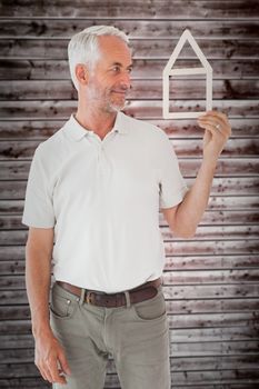 Happy man holding house outline  against wooden planks