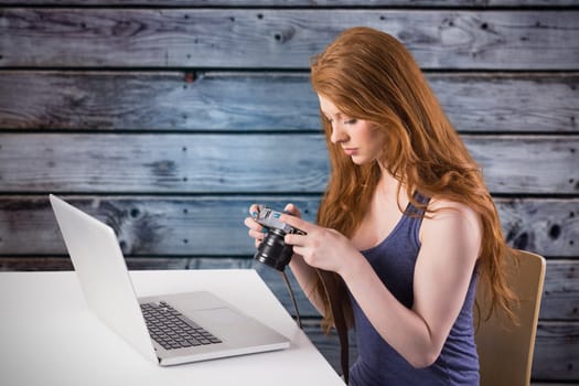 Pretty redhead working on laptop against grey wooden planks