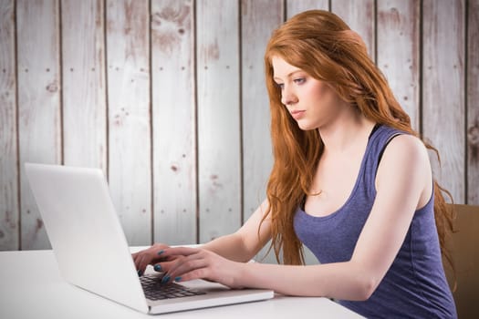 Pretty redhead working on laptop against wooden planks