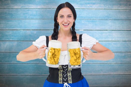 Pretty oktoberfest girl holding beer tankards against wooden planks