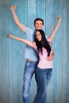 Young couple cheering at camera against wooden planks