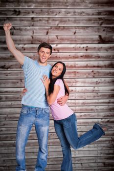 Young couple cheering at camera against wooden planks