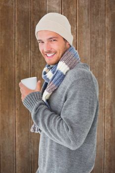 Handsome man in winter fashion holding mug against wooden planks background