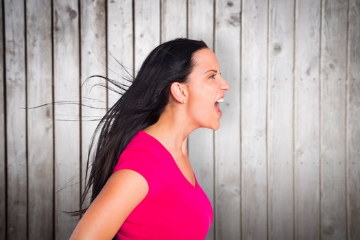 Young brunette shouting in tshirt against wooden planks