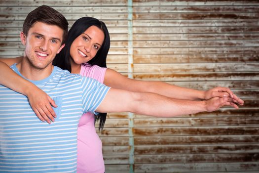 Young couple smiling at the camera against wooden planks