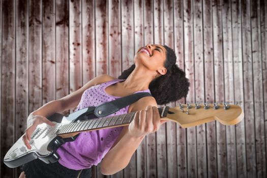 Pretty girl playing guitar against wooden planks
