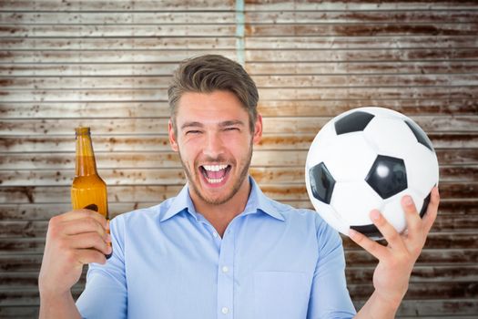 Handsome young man holding ball and beer against wooden planks