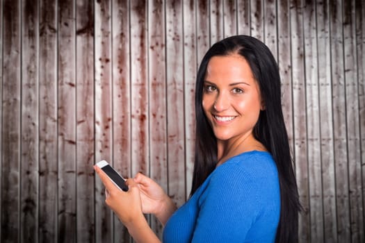 Young brunette sending a text against wooden planks