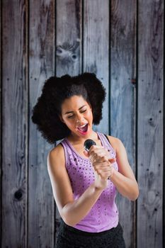 Pretty girl singing against grey wooden planks