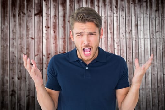 Handsome young man shrugging shoulders against wooden planks