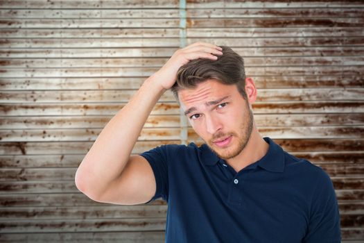 Handsome young man looking confused against wooden planks