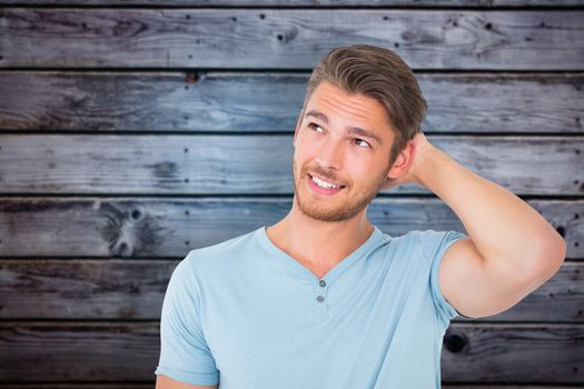 Young man posing with hands on head  against grey wooden planks