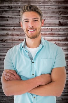 Handsome young man posing with arms crossed against wooden planks