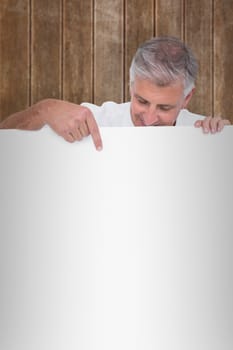 Casual man showing a poster against wooden planks background
