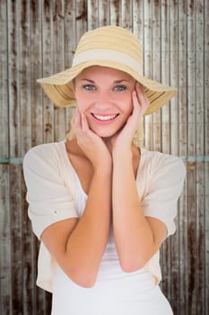 Attractive young blonde smiling at camera in sunhat against wooden planks