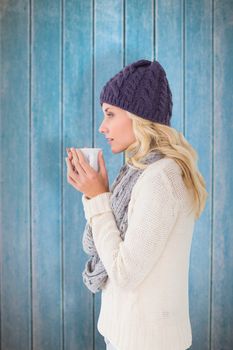 Pretty blonde in winter fashion holding mug against wooden planks