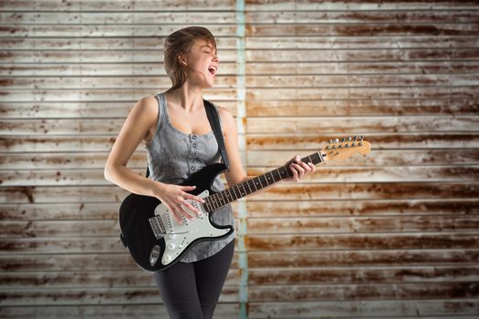 Pretty young girl playing guitar against wooden planks