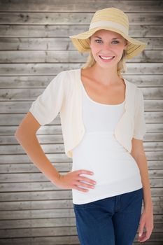 Attractive young blonde smiling at camera in sunhat against wooden planks background