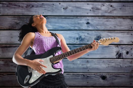 Pretty girl playing guitar against grey wooden planks