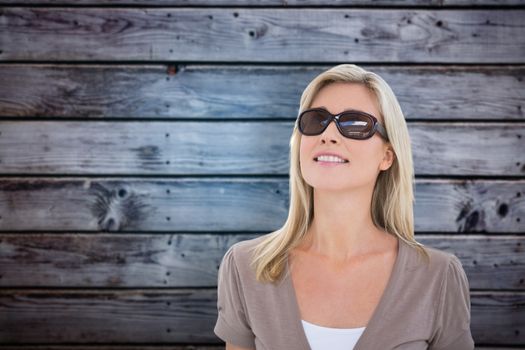 Happy blonde wearing sun glasses against grey wooden planks