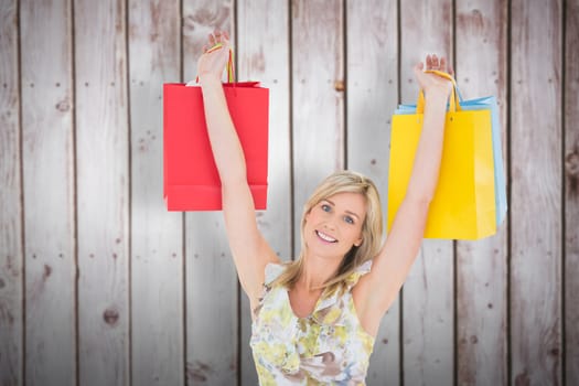 Happy blonde with shopping bags against wooden planks